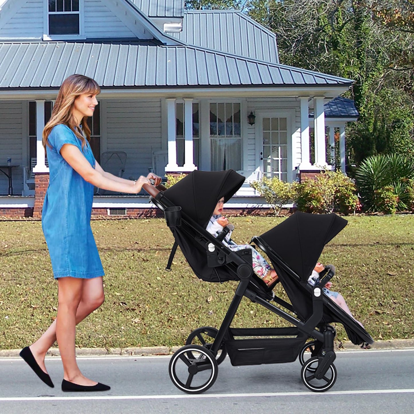 Black tandem stroller with reversible seats, adjustable canopies, large storage basket, and one-hand fold, designed for twins and newborns.